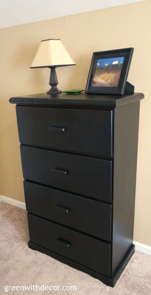 A black painted dresser near a tan wall and tan carpet