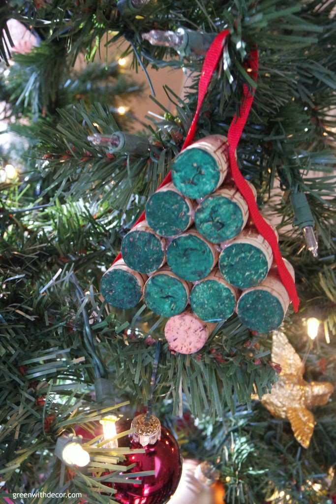 A cute Christmas tree ornament made of wine cork and ribbon hangs on a tree.