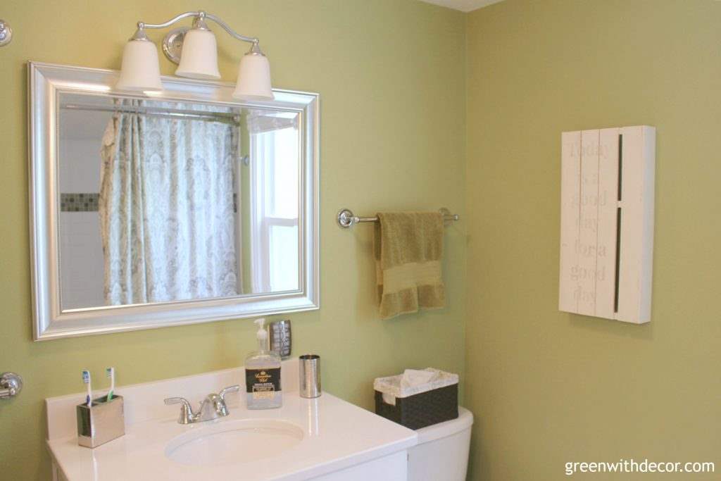 A DIY liquor bottle soap dispenser in a green and white bathroom