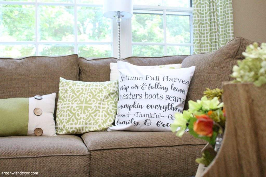 White and green fall throw pillows on a brown couch
