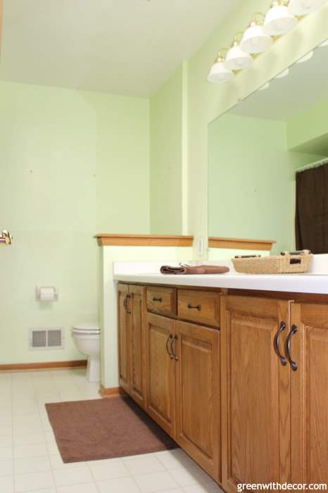A photo of a bathroom with pale green walls, brown towels and light brown cabinets.