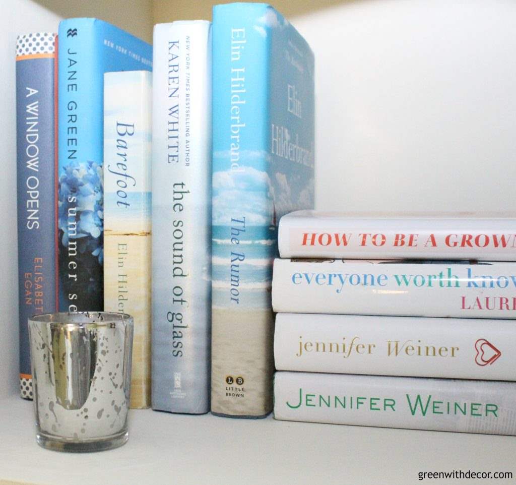 A white painted bookshelf with blue and white books.