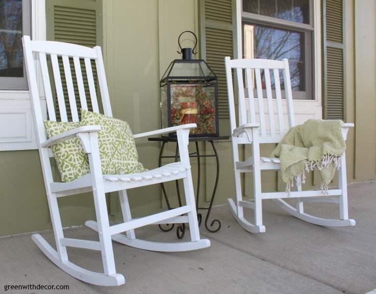 Two white rocking chairs sit in front of a home