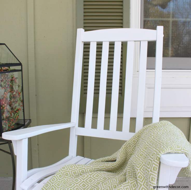 A white rocking chair sits with a blanket thrown across it