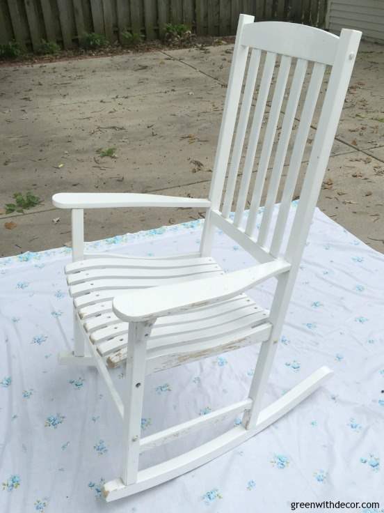 A white rocking chair sits on a sheet in a driveway