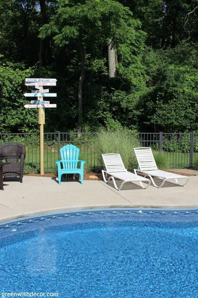 Destination arrow signs are a fun addition to your yard. Here's one along a fence with some lounge chairs.
