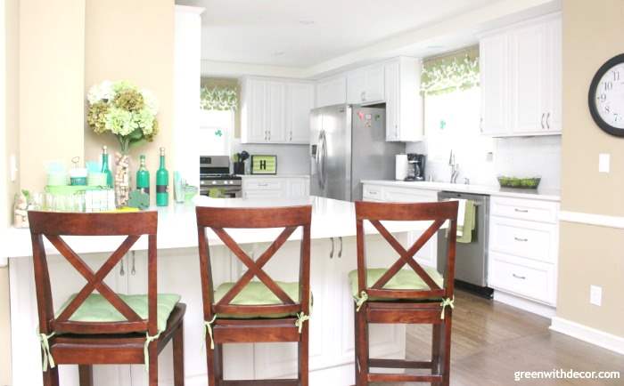 A tan kitchen with brown bar chairs aligned at the bar.