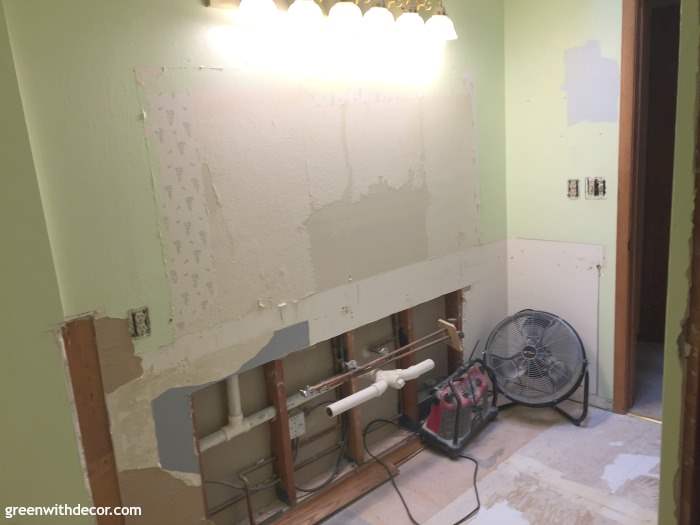 A bathroom during demolition, with the mirrors and cabinet removed.