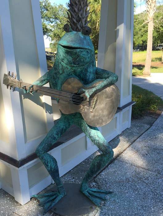 A statue of a frog playing a guitar at a restaurant in Folly Beach.