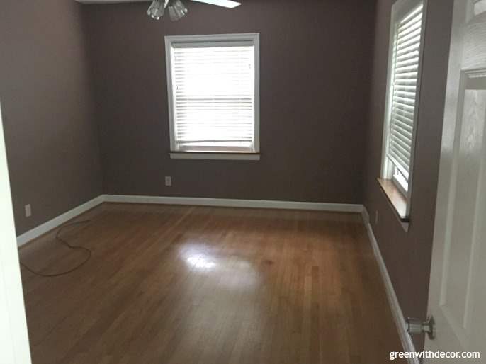 A bedroom with brown walls and hardwood floors