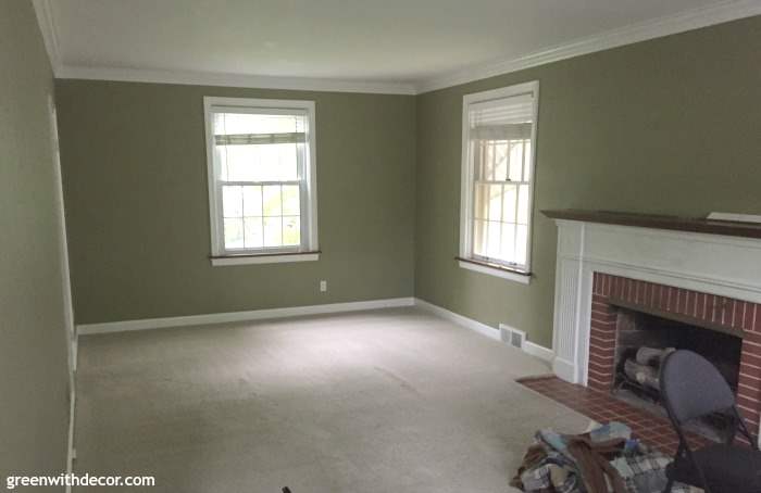 A green painted living room with a white and red brick fireplace