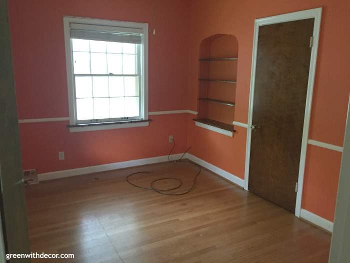 An orange bedroom with hardwood floors and built-in shelves