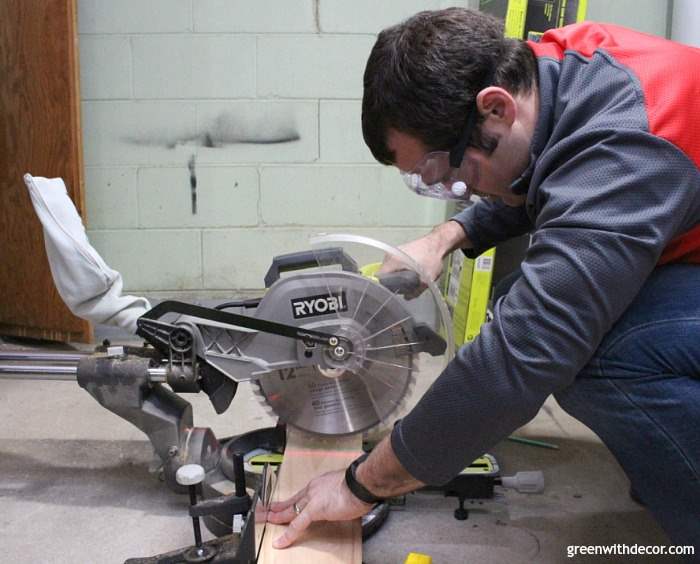 A man wearing protective eye gear cuts wood with a Ryobi saw