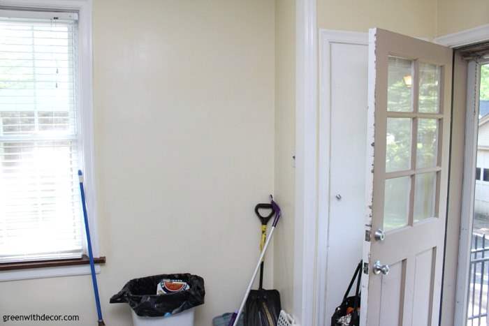 The foyer sits with an open door, garbage can and some shovels and brooms