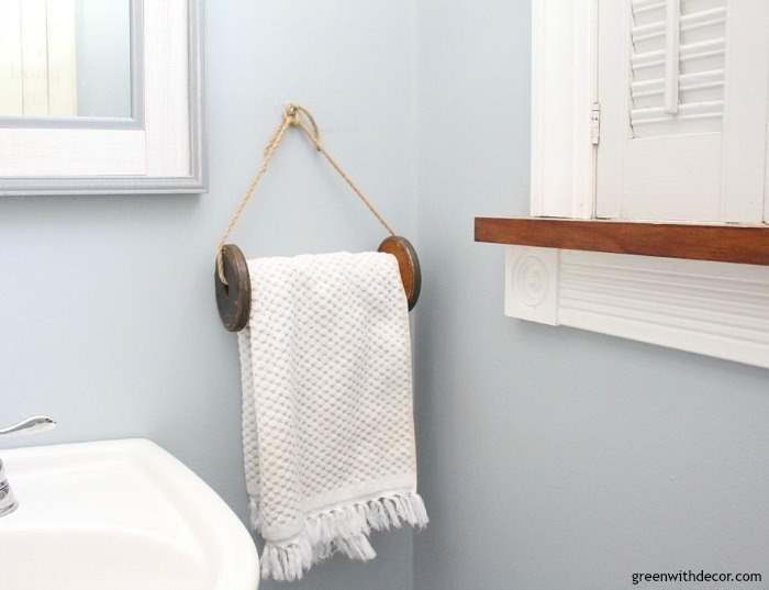 Krypton blue bathroom with a wooden spool towel rack, white hand towel with fringe and a silver faucet.