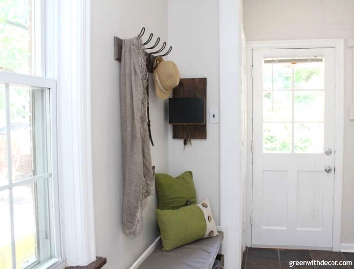 The foyer with a white door, bench seating and hooks on the wall