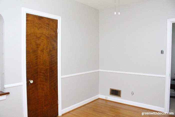 A newly painted grey room with white trim and a brown door