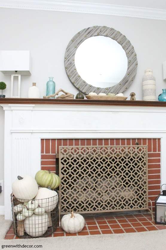 A fireplace with the mantel decorated for fall in a spring, coastal theme.