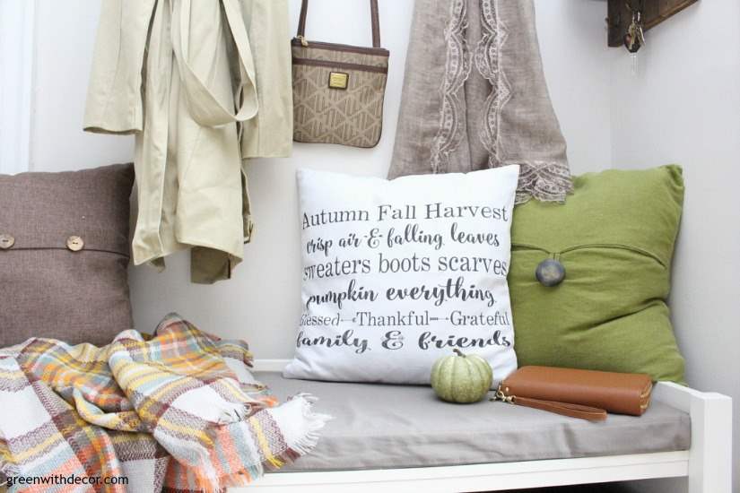 Fall mudroom with pillows, a green pumpkin and a plaid scarf