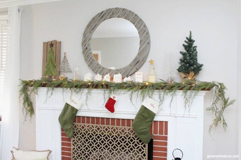 A simple Christmas mantel with village pieces, pretty faux garland and white lights