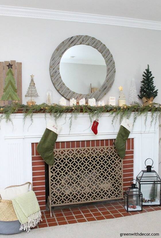 A simple Christmas mantel with village pieces, that faux garland looks real - I love it with the white Christmas lights and all the mini Christmas trees, so easy and festive!