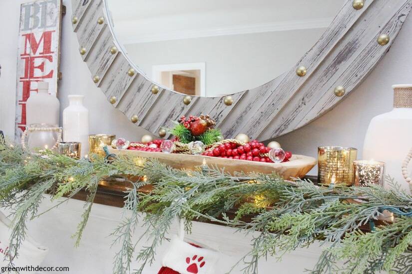 A Christmas mantel with a gray and gold mirror