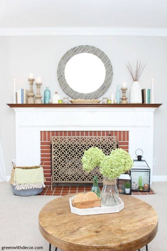 A simple coastal mantel using wood candlesticks, books and glass vases