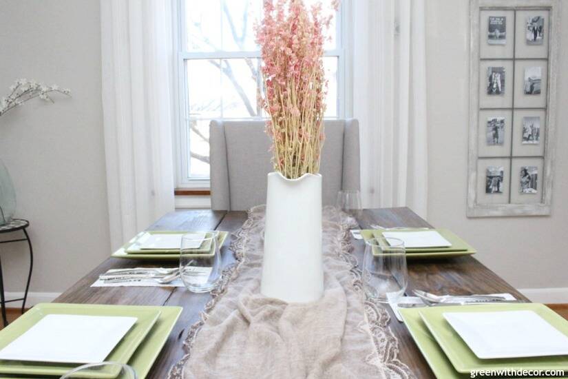 An easy Valentine's Day centerpiece and tablescape with a pretty lace scarf as a table runner and pink flowers in a white pitcher.