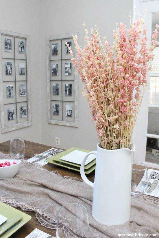 An easy Valentine's Day centerpiece and tablescape with a simple lace scarf as a table runner and pink flowers in a white pitcher.