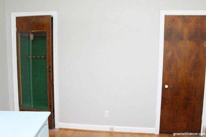 A bedroom with gray walls, wood doors and white trim