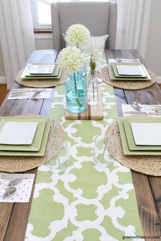 An easy aqua and green coastal spring tablescape - perfect for a spring dinner or Easter brunch! The farmhouse table looks great with the green and white table runner - would you believe it's actually a window valance? Such a good reuse for an old valance!