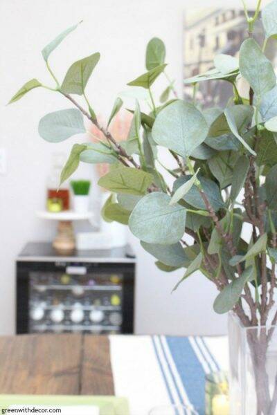 Faux eucalyptus with a wine fridge in the background
