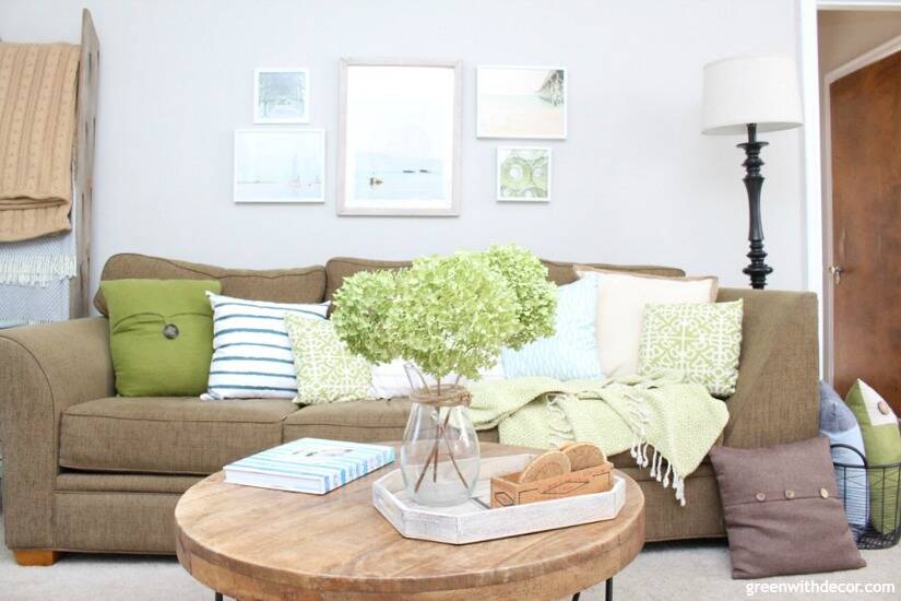 Beautiful spring coastal living room - love the aqua, white, green and blue pillows with those green hydrangeas and boat artwork!