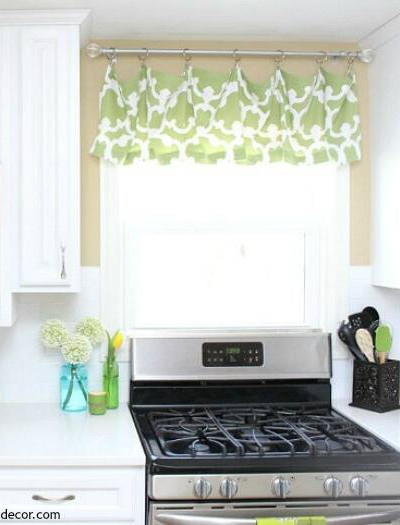 White kitchen with green and white window valance, stainless steel stove and white quartz counters