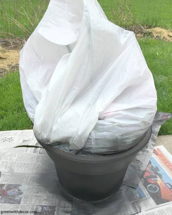 A spray painted plastic outdoor planter covered in plastic