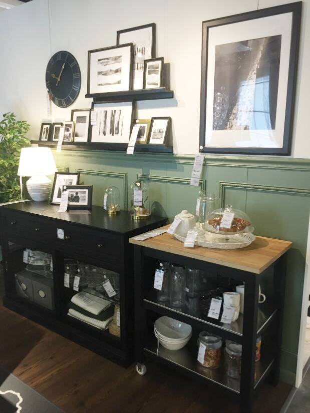 Green half wall with black shelving and black frames above