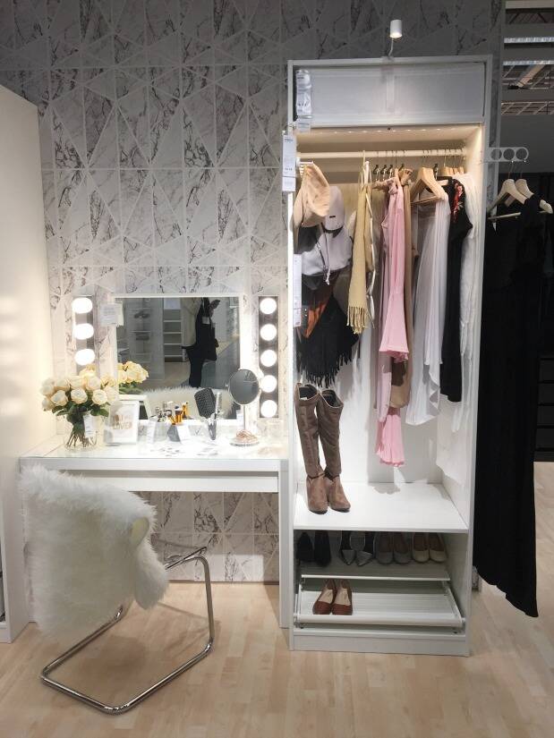 White and gray closet with a vanity and clothes hanging