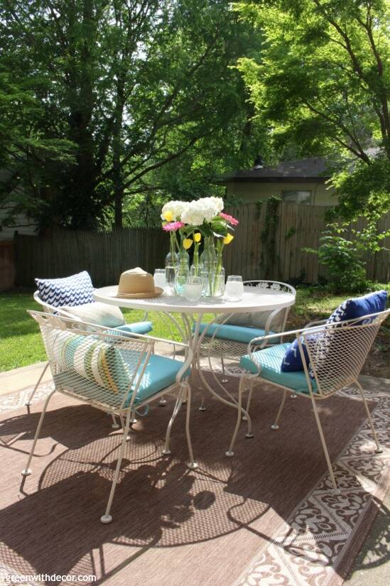 A blue and white patio with colorful outdoor pillows, aqua cushions and a flower centerpiece