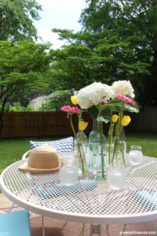 A tan metal patio set with flowers and a summer hat on top