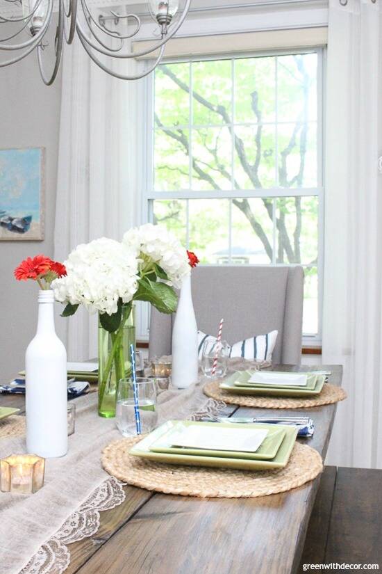 A Fourth of July table with a brown table runner, white hydrangeas and red flowers