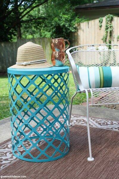 A spray painted outdoor table with a summer hat and copper mugs on top