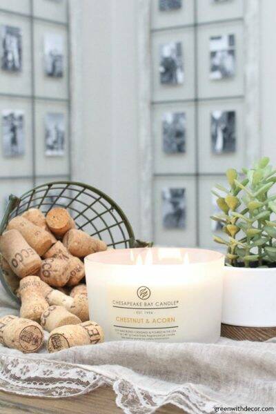 White Chestnut & Acorn candle surrounded by a faux plant and wine corks