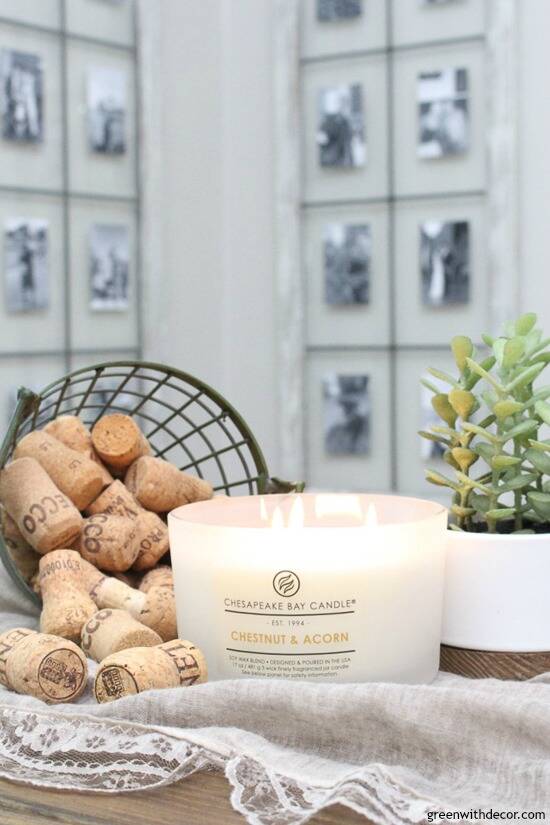 White Chestnut & Acorn candle surrounded by a faux plant and wine corks