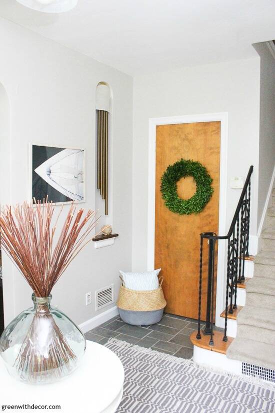 Gray coastal foyer with boat artwork, a boxwood wreath and a seagrass basket