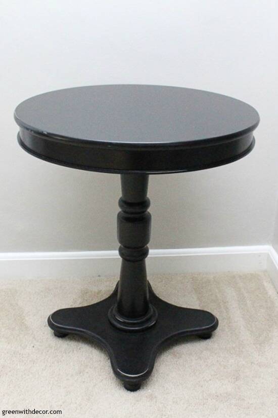 A black round table in front of a gray wall