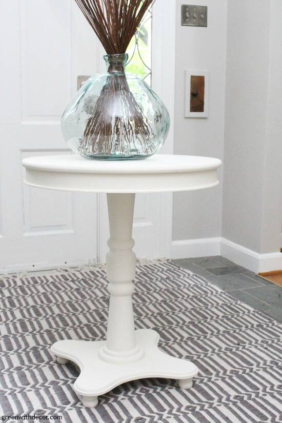 A round white painted table in a gray coastal farmhouse foyer