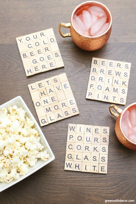 Scrabble tile DIY coasters near copper mugs and a white bowl of popcorn