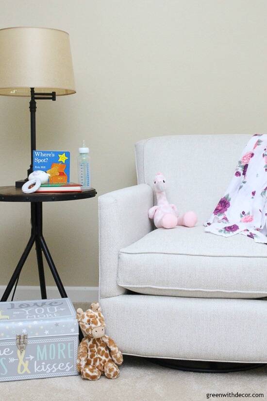 A neutral glider with a floral swaddle blanket and stuffed animals