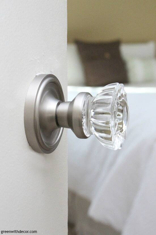Crystal door knobs with silver plate on a white door looking into a white bedroom