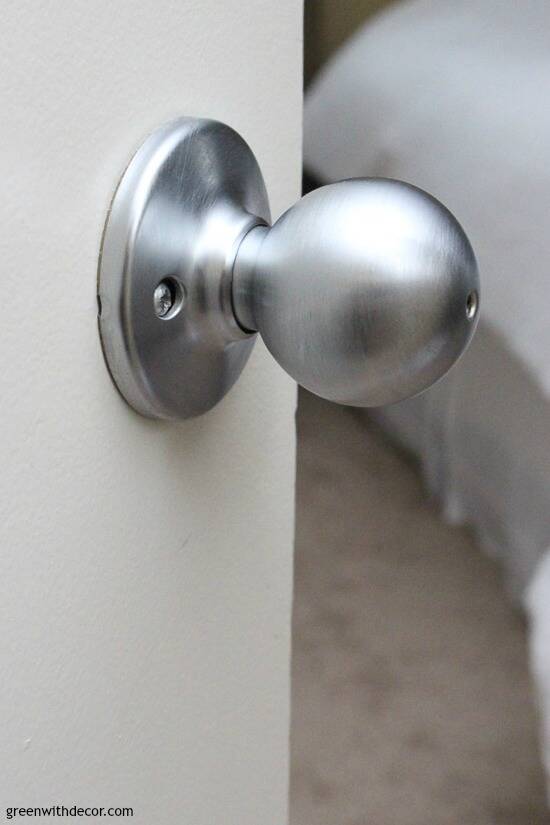 White door with silver door knob looking into a bedroom